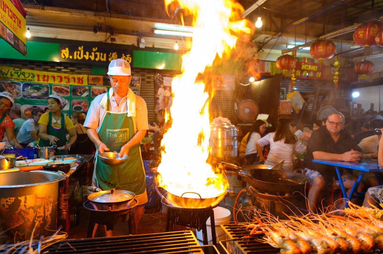 Street food chef cooking with fire at Yaowarat road in Bangkok